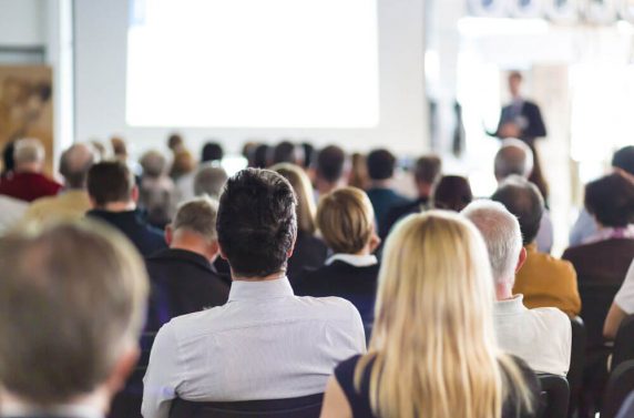 A group of people sitting in front of a projector screen.