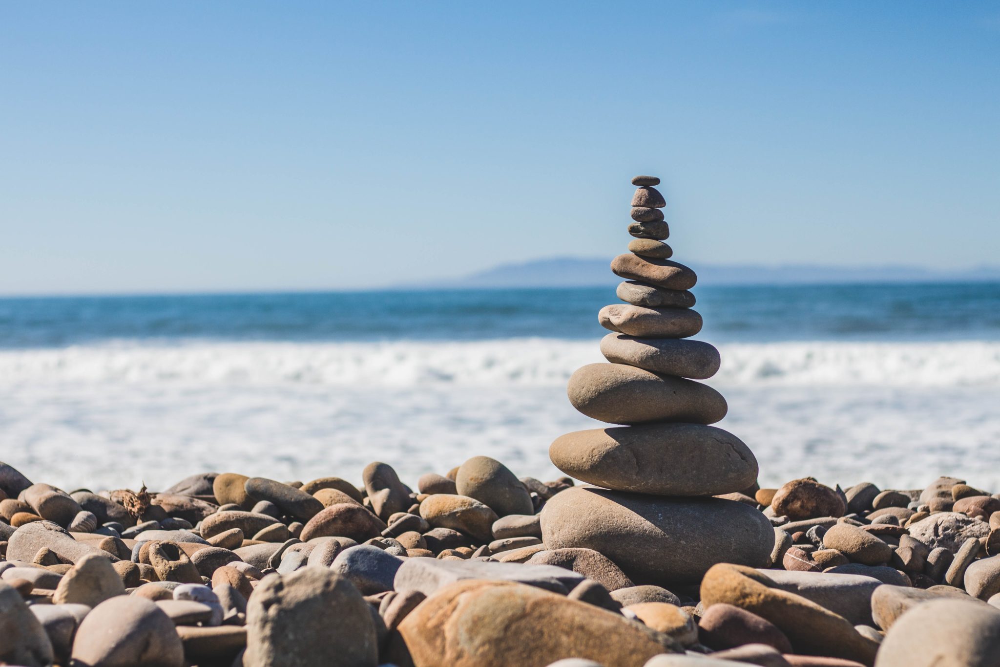 A stack of rocks on the beach near water.