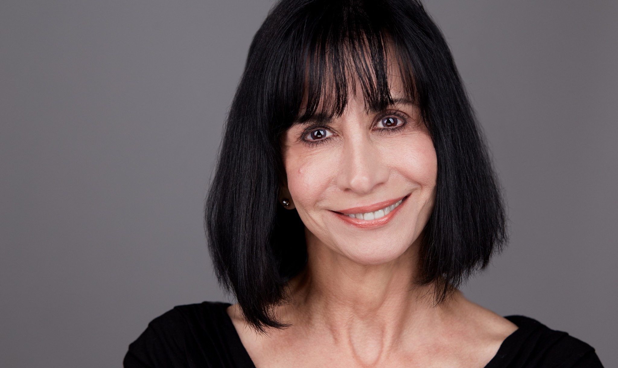 A woman with black hair and bangs smiles for the camera.