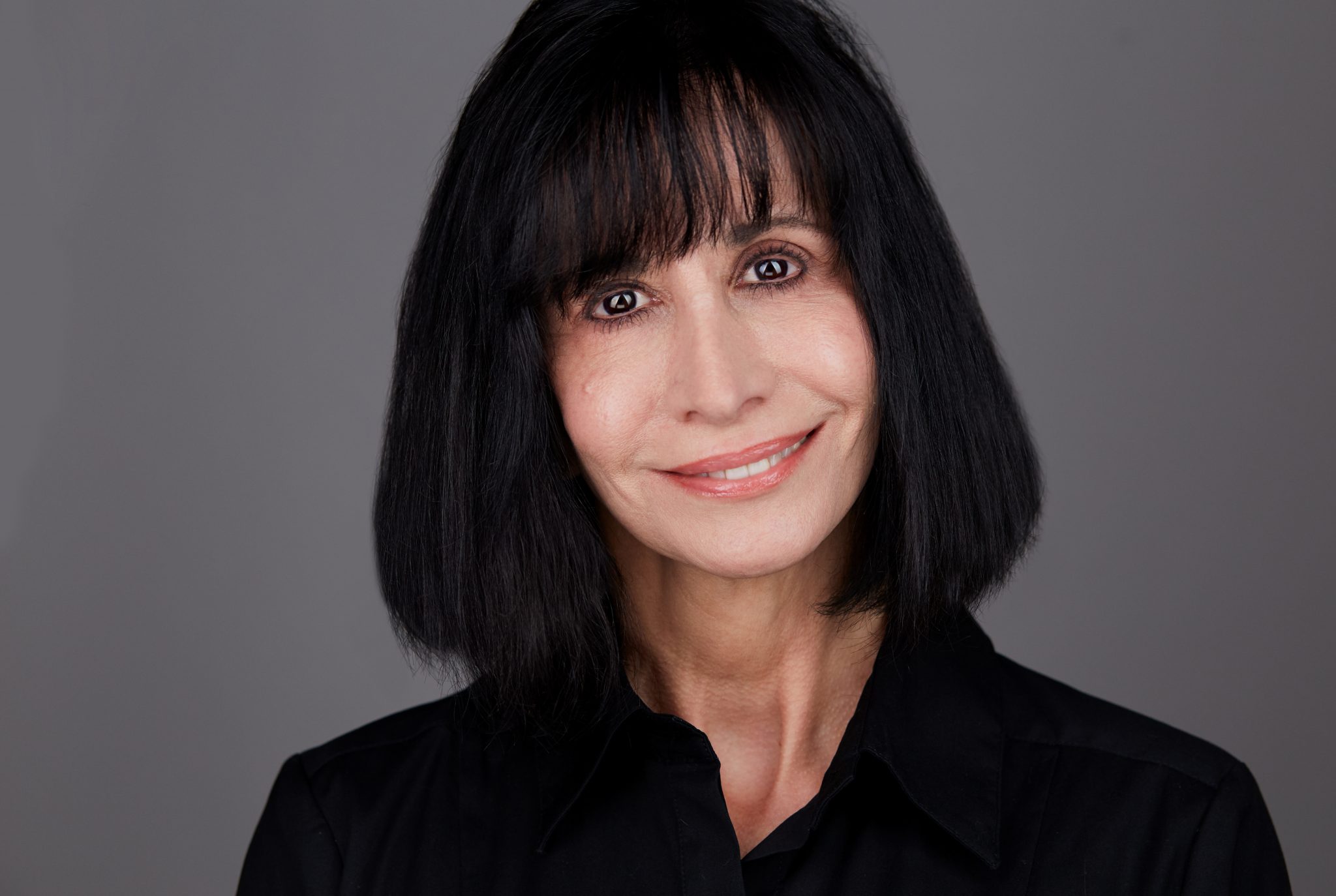 A woman with black hair and bangs smiles for the camera.